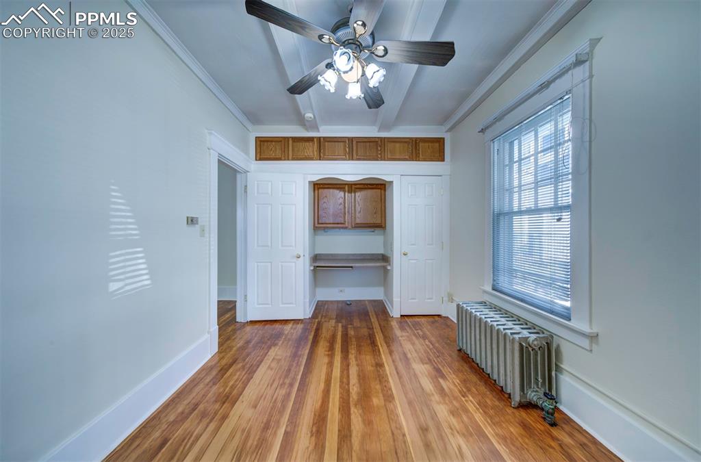 Image 31 of 40: Unfurnished bedroom featuring crown molding, radiator heating unit, light w
