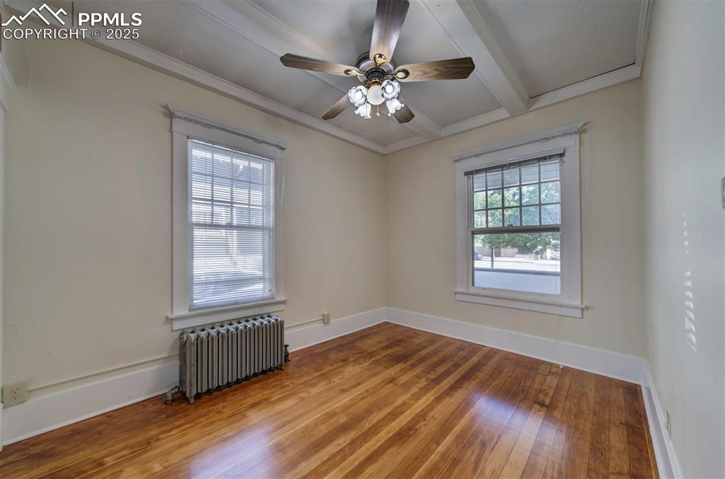 Image 33 of 40: Unfurnished room featuring radiator heating unit, hardwood / wood-style flo