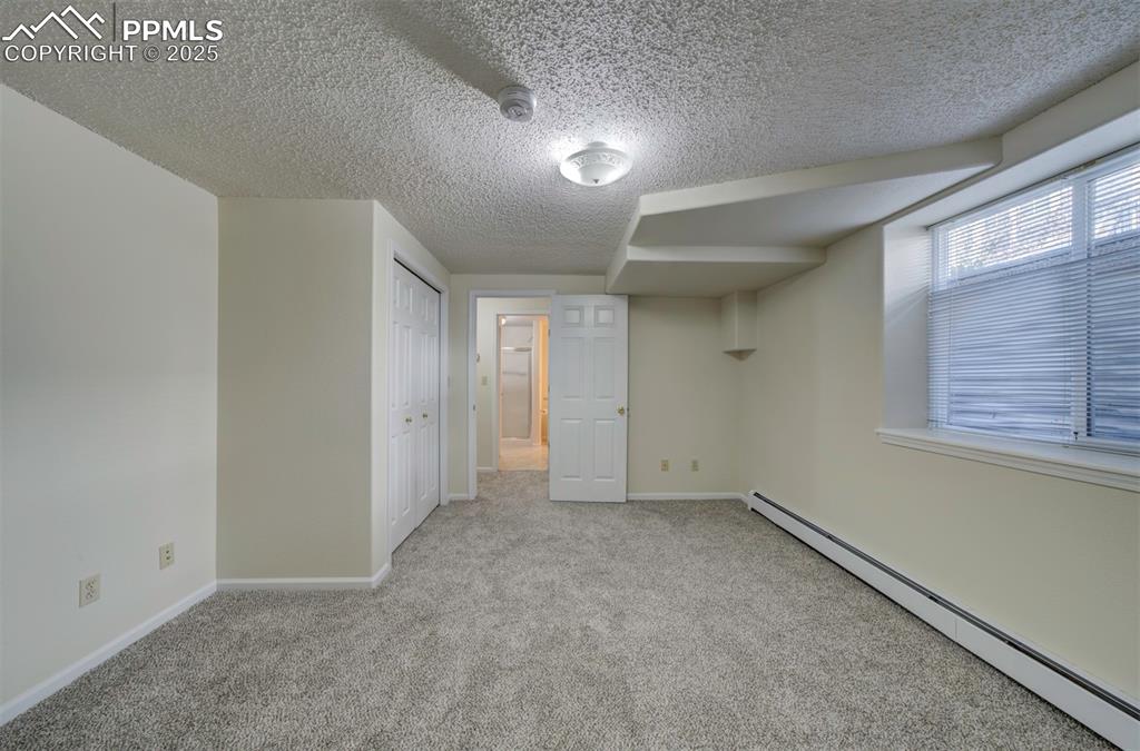 Image 35 of 40: Unfurnished bedroom with a baseboard radiator, light carpet, and a closet