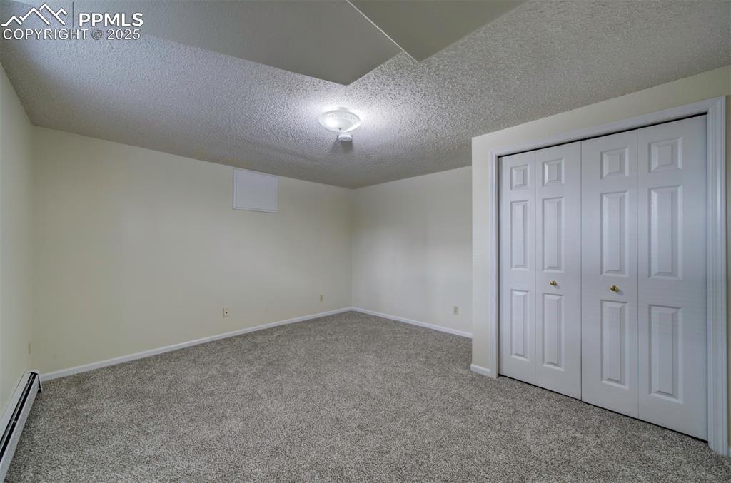 Image 36 of 40: Unfurnished bedroom with a textured ceiling, baseboard heating, carpet, and