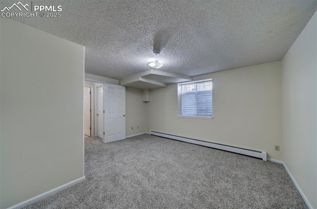 Image 37 of 40: Below grade area featuring a baseboard radiator, carpet floors, and a textu