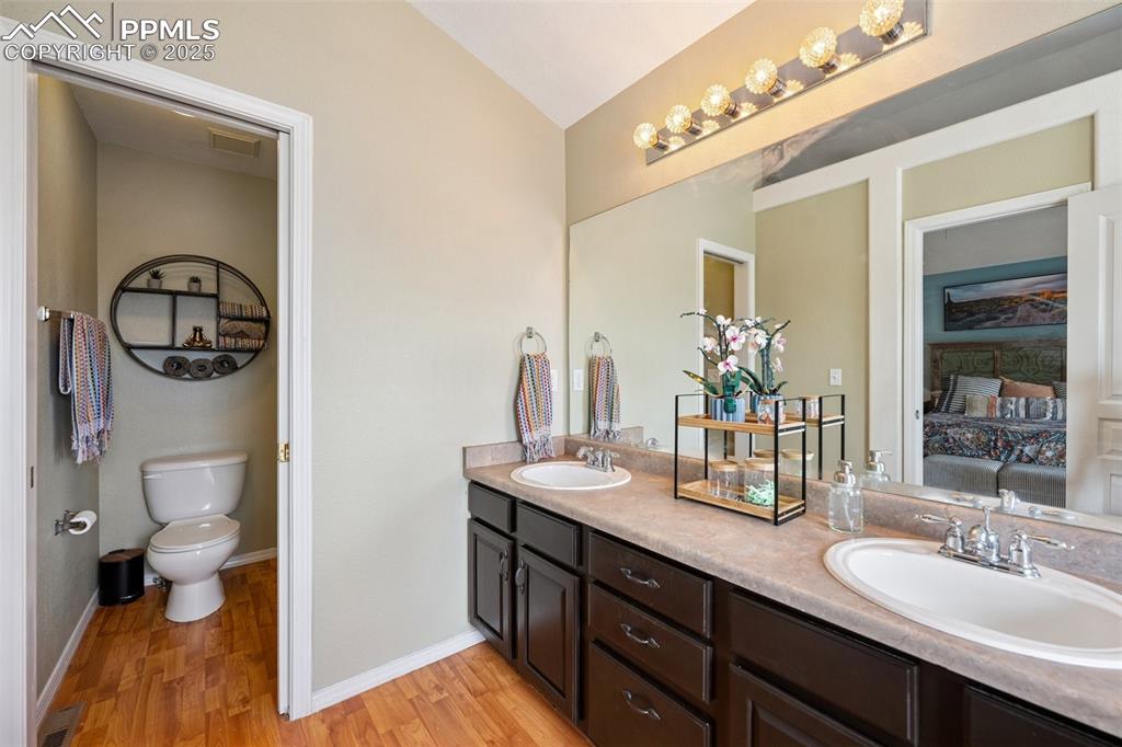 Image 26 of 40: Full bath featuring double vanity and wood vinyl finished floors