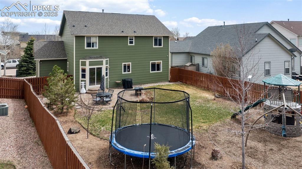 Image 5 of 40: Rear view of property with a patio, a fenced backyard, central AC unit, a t