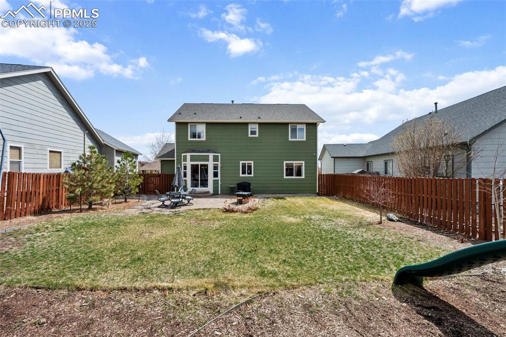 Image 9 of 40: Back of house with a patio, a fenced backyard, and a yard