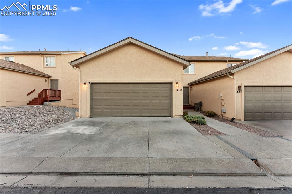 Caption: Traditional-style home with stucco siding, driveway, and a garage