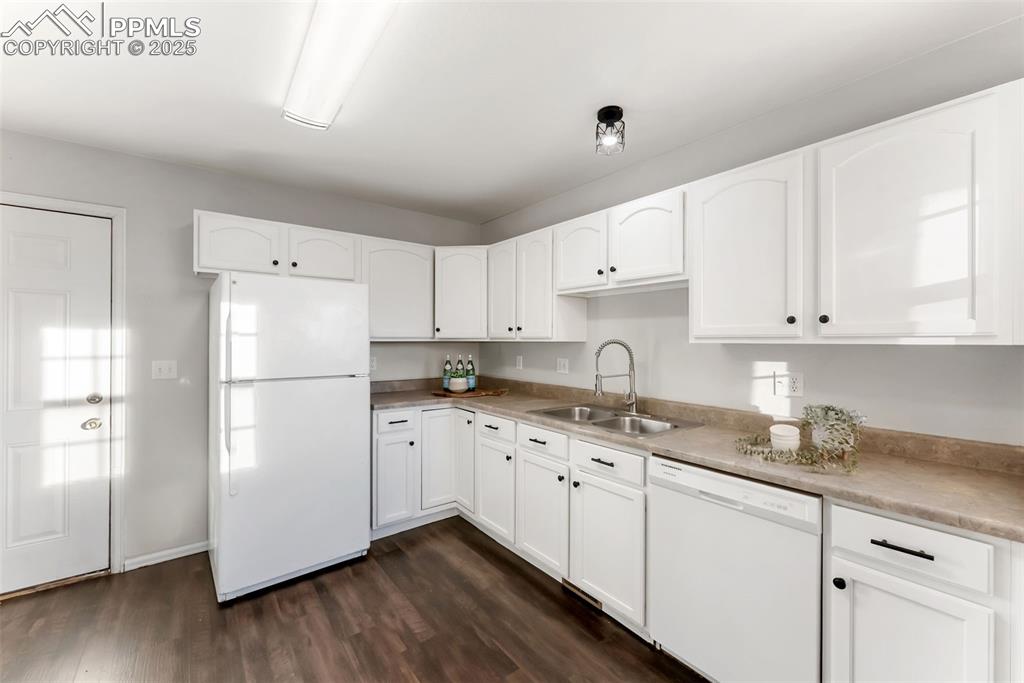 Image 10 of 45: Kitchen featuring white appliances, white cabinets, dark wood-style floorin