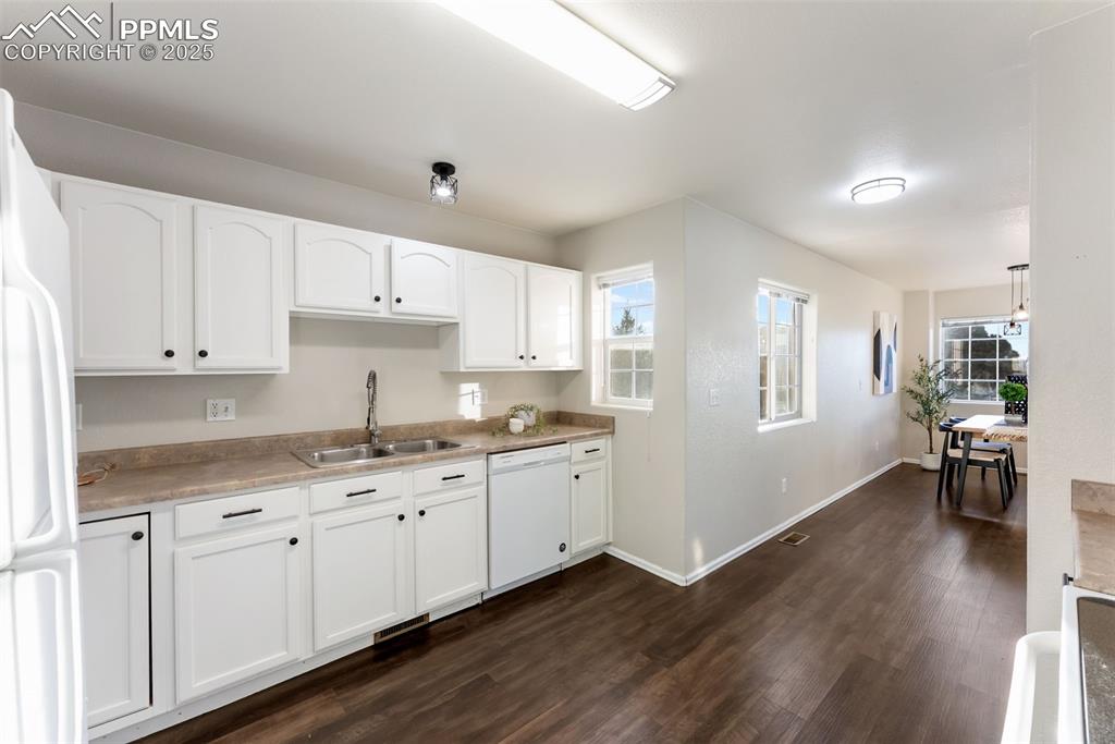Image 12 of 45: Kitchen featuring white appliances, white cabinets, dark wood finished floo
