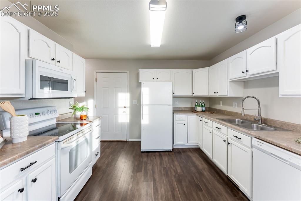 Image 13 of 45: Kitchen with white appliances, white cabinets, dark wood-style floors, and