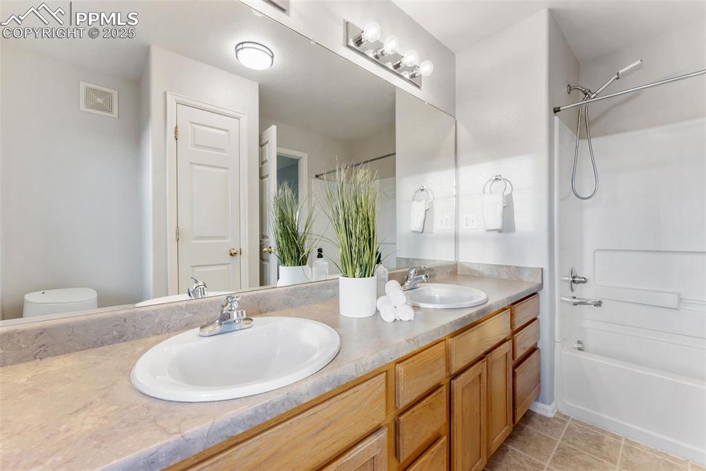 Image 18 of 45: Bathroom with double vanity, shower / tub combo with curtain, and light til