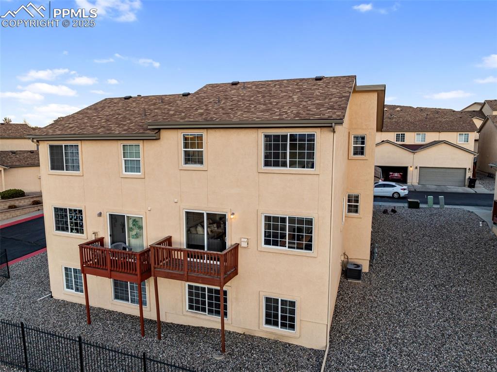 Image 42 of 45: Rear view of property featuring a wooden deck, stucco siding, and roof with