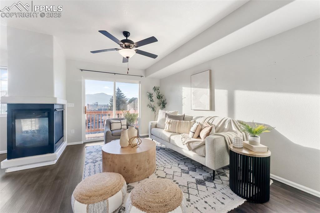 Image 5 of 45: Living room with dark wood-type flooring, a multi sided fireplace, and a ce