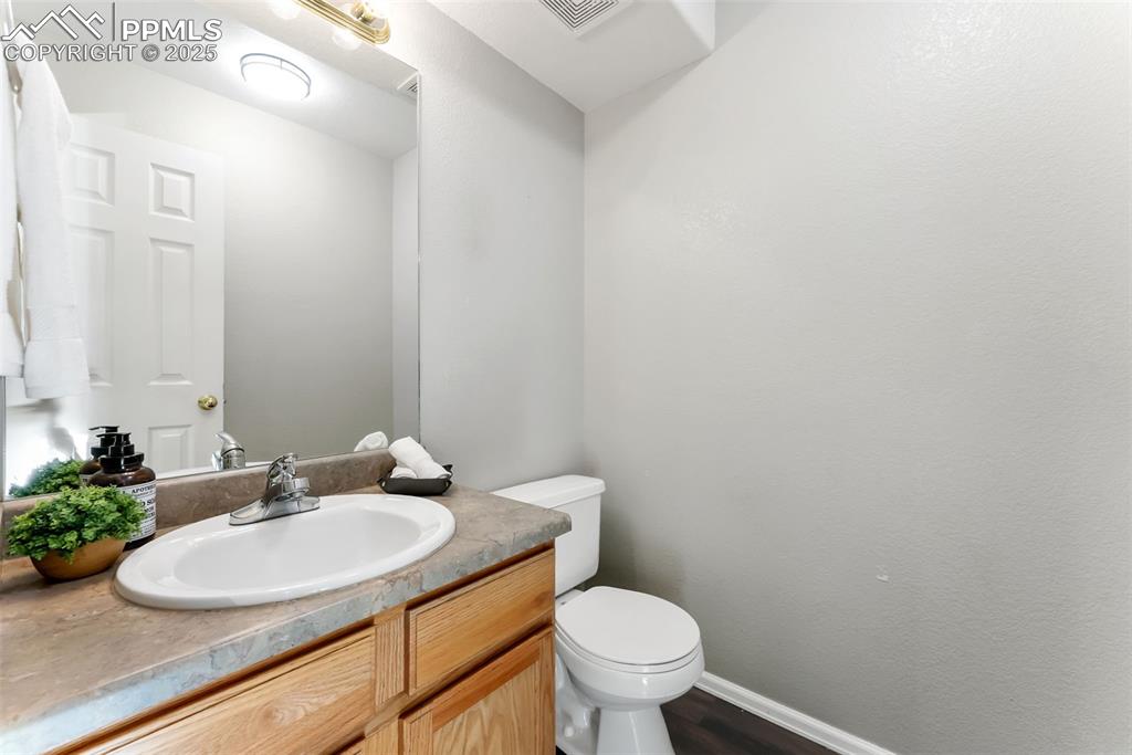Image 9 of 45: Half bathroom with vanity and dark wood-style floors