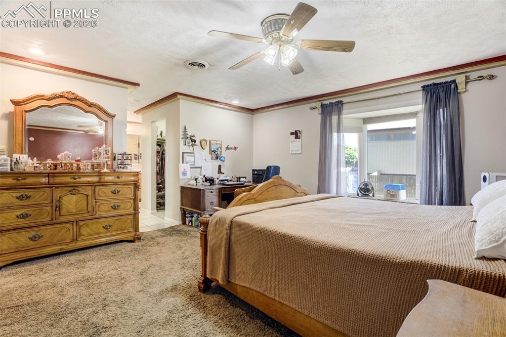 Image 17 of 50: Primary Bedroom with light colored carpet, ceiling fan, a textured ceiling,
