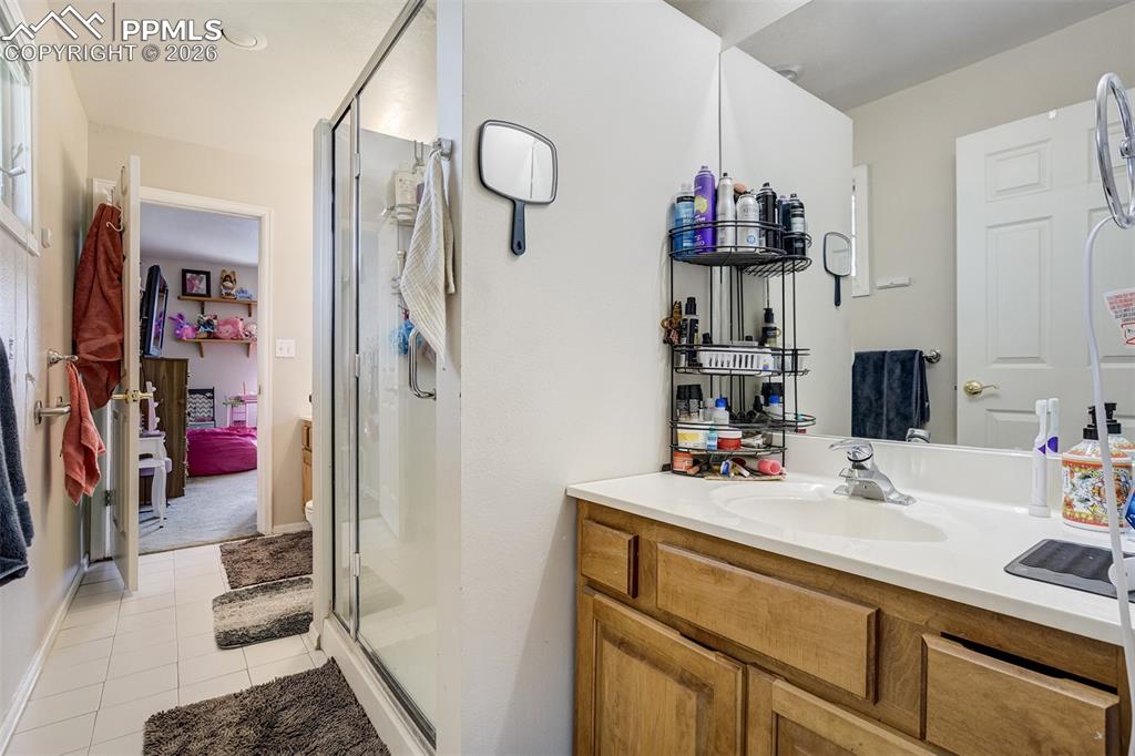 Image 23 of 50: Bathroom attached to both bedrooms,  shower stall,  2 vanities, and light t