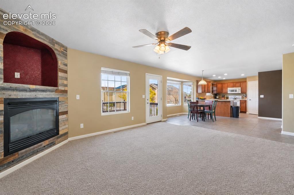 Image 18 of 49: Spacious living area featuring a fireplace with wood-finish surround, carpe