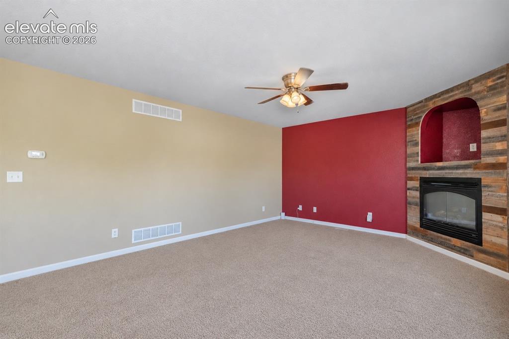 Image 19 of 49: Carpeted flooring, recessed fireplace with a wood-finish surround, arched a