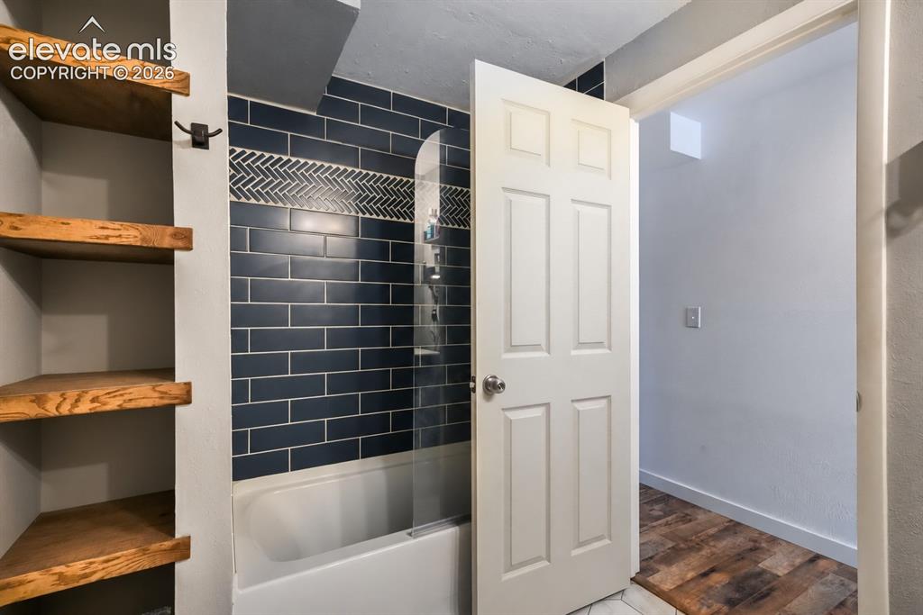 Image 40 of 49: Built-in corner shelving, subway tile shower surround with a herringbone ac