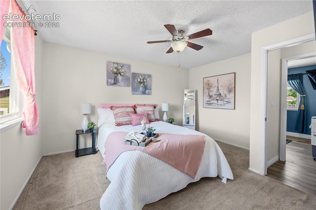 Image 15 of 31: Upper Level Primary Bedroom with neutral carpet, a lighted ceiling fan, and