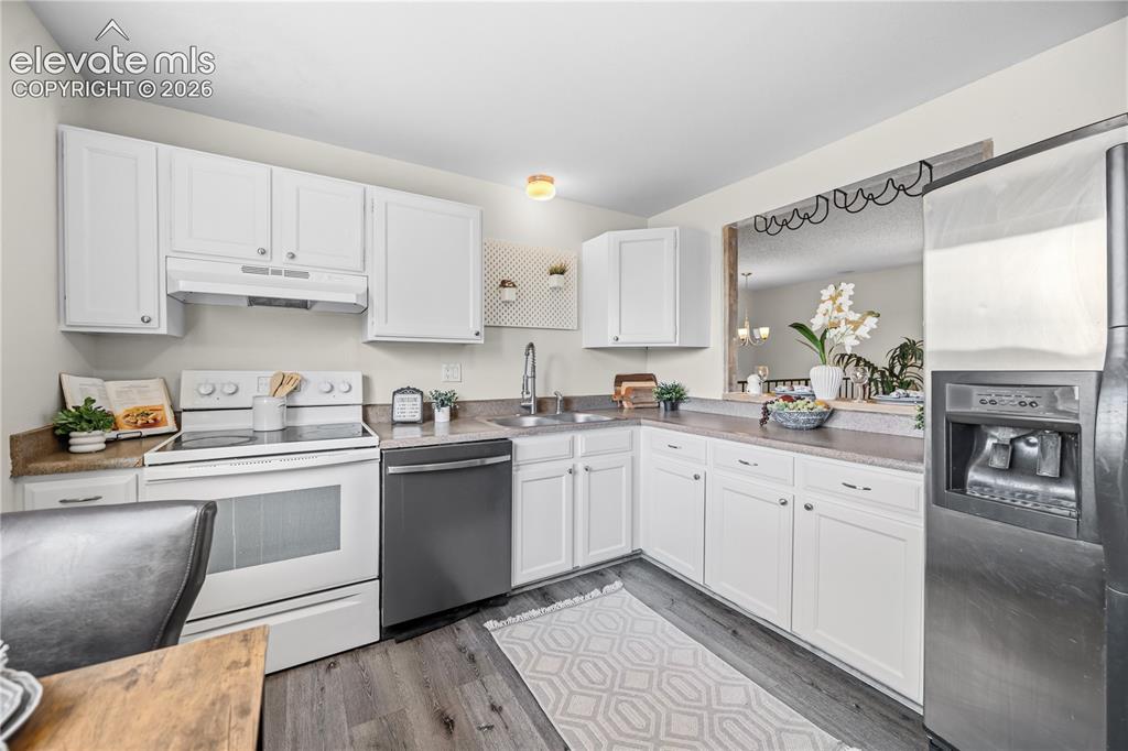 Image 9 of 31: The Kitchen boasts white cabinetry, solid countertops, & a full suite of ap