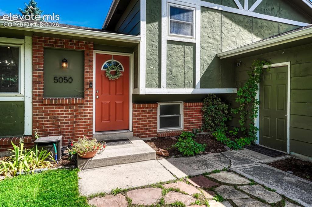 Image 3 of 50: Attractive brick accents, red door, and flagstone patio add to the personal