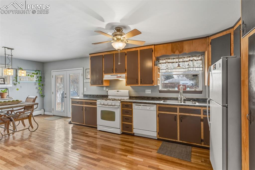 Image 14 of 37: Kitchen featuring white appliances, hanging light fixtures, dark countertop
