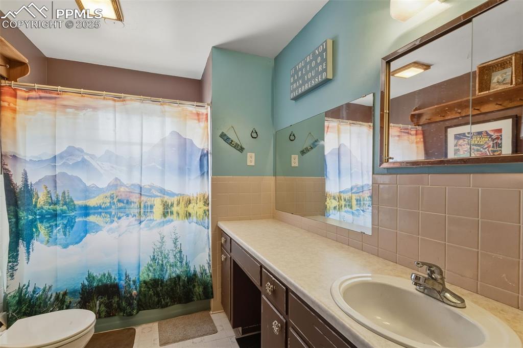 Image 20 of 37: Bathroom featuring vanity, decorative backsplash, tile walls, shower / tub