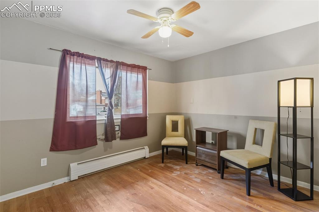 Image 21 of 37: Living area with a baseboard radiator, light wood-style floors, and a ceili