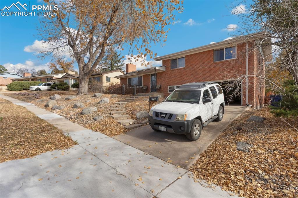 Image 27 of 37: Tri-level home featuring concrete driveway, brick siding, an attached garag