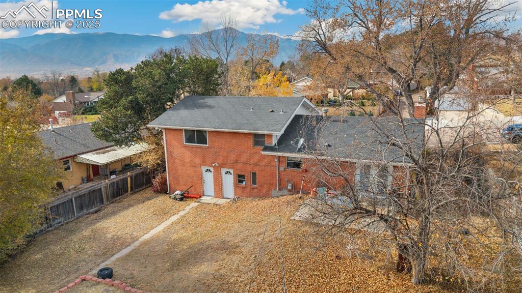 Image 31 of 37: Rear view of house with brick siding, a mountain view, a chimney, and roof