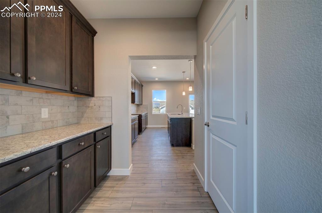 Image 10 of 47: Kitchen featuring backsplash, light hardwood / wood-style floors, light sto