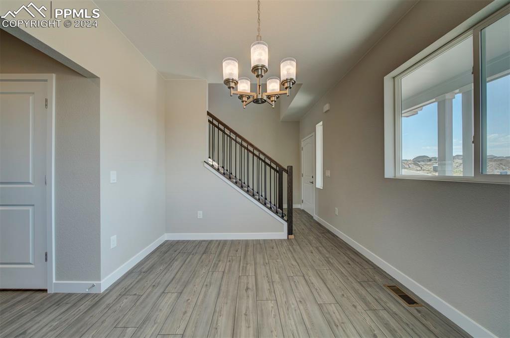 Image 12 of 47: Empty room featuring a chandelier and light wood-type flooring
