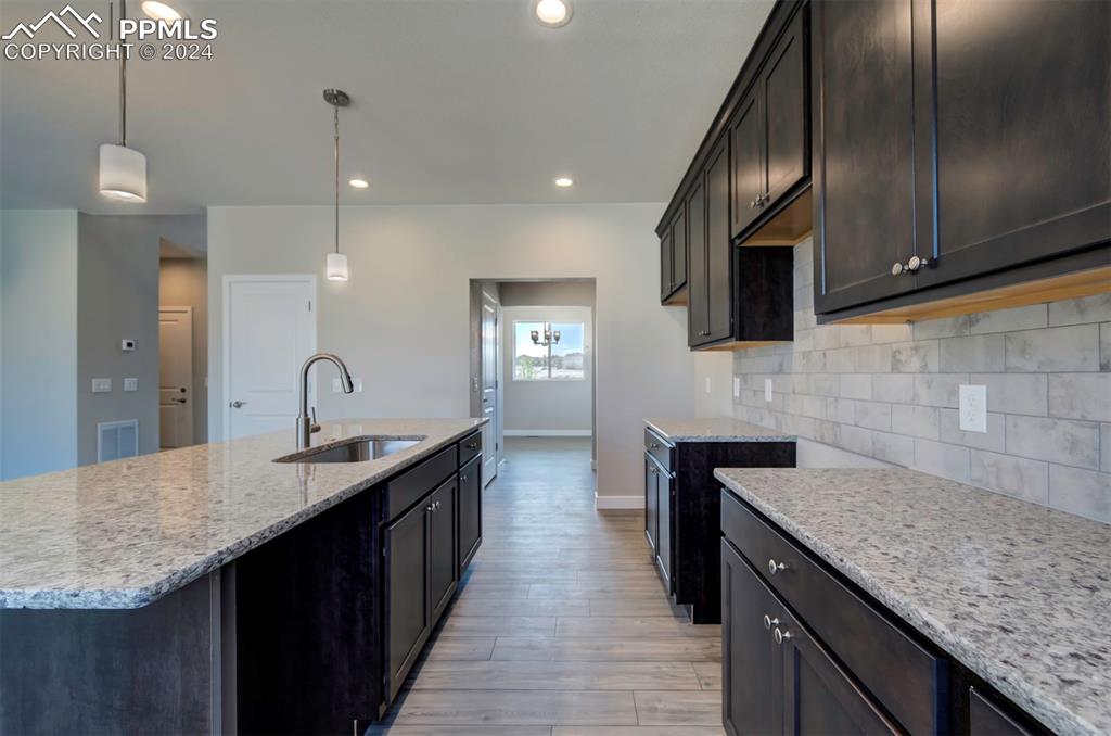 Image 3 of 47: Kitchen featuring backsplash, sink, a center island with sink, light wood-t