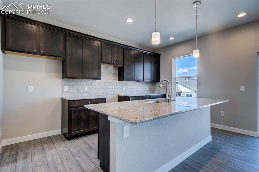 Image 4 of 47: Kitchen with backsplash, sink, decorative light fixtures, dark brown cabine
