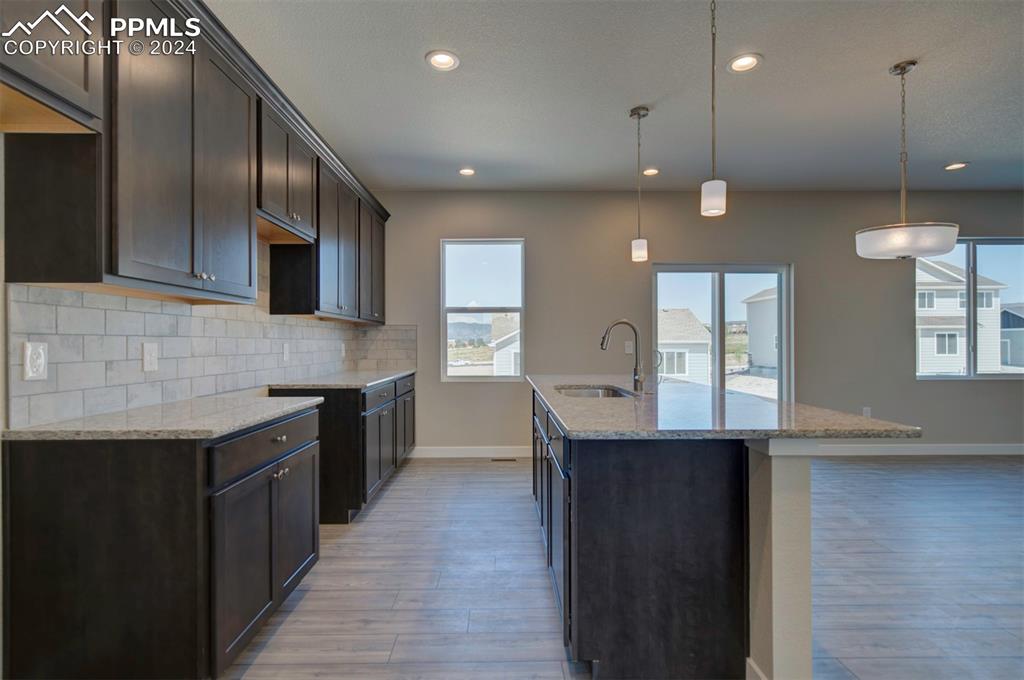 Image 5 of 47: Kitchen featuring decorative backsplash, an island with sink, light wood-ty