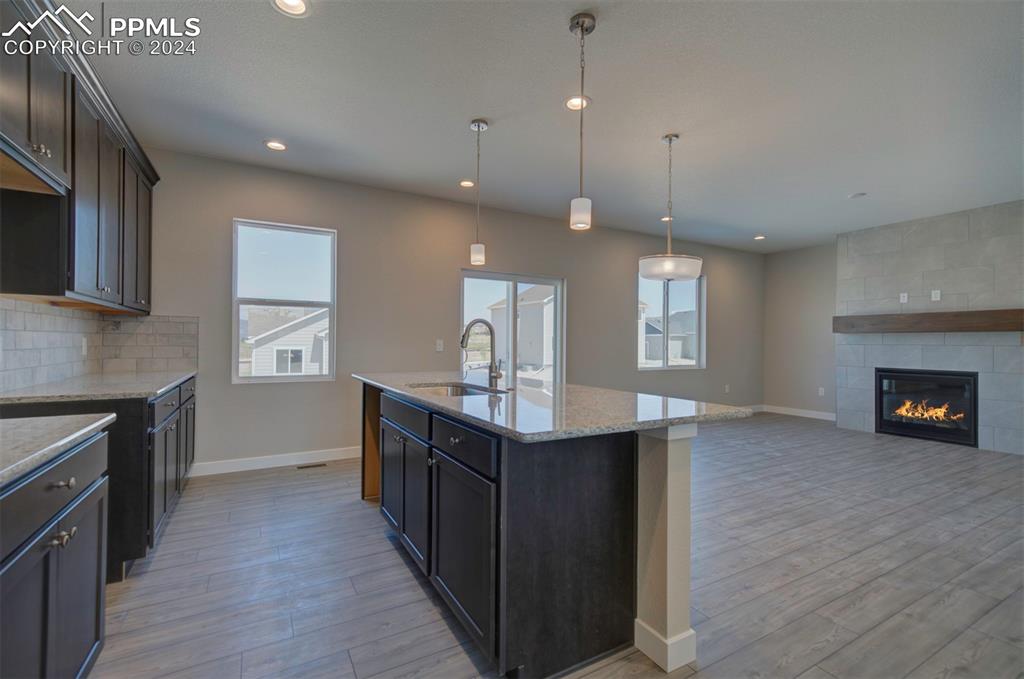 Image 6 of 47: Kitchen with sink, decorative backsplash, a kitchen island with sink, light
