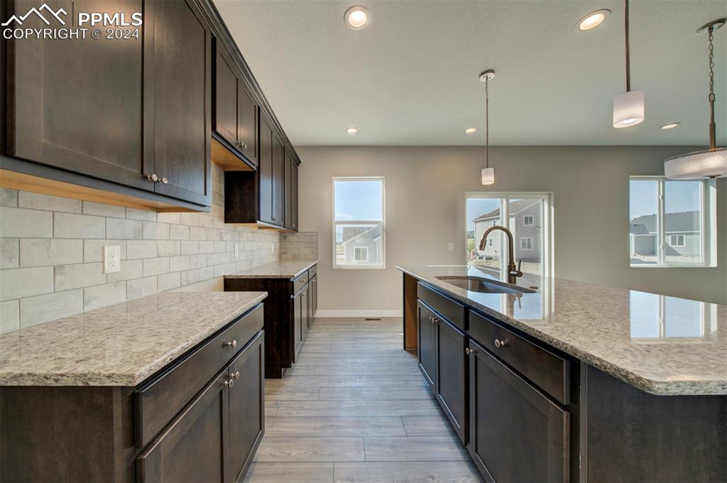 Image 7 of 47: Kitchen with sink, light wood-type flooring, decorative backsplash, hanging
