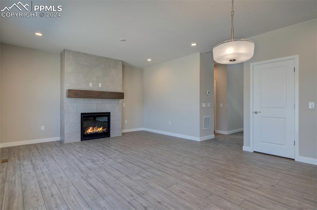 Image 9 of 47: Unfurnished living room with tile walls, light hardwood / wood-style floori