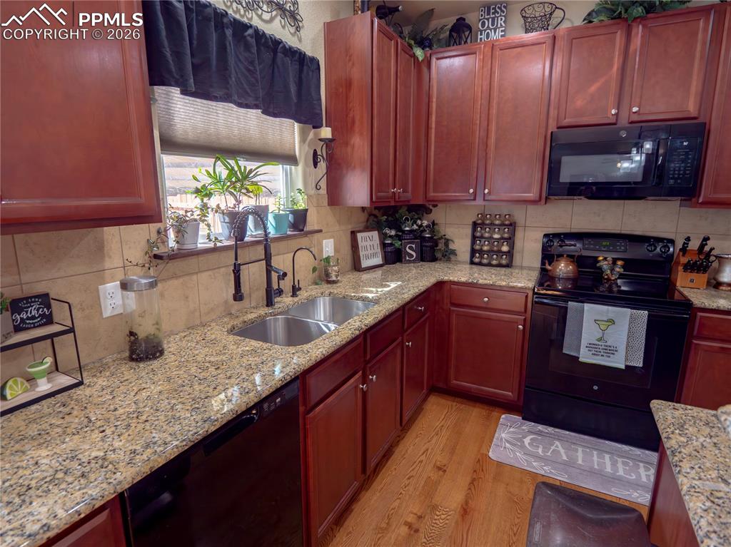 Image 10 of 32: Kitchen featuring black appliances, light stone counters, and decorative ba