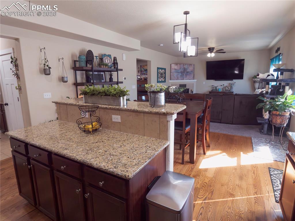 Image 11 of 32: Kitchen featuring a center island, a ceiling fan, light stone countertops, 