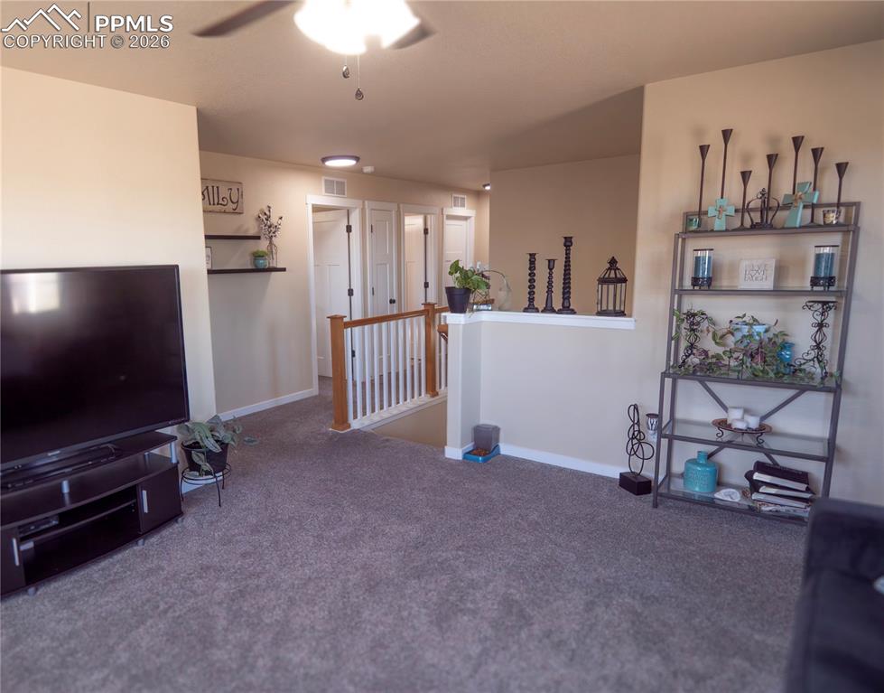 Image 17 of 32: Carpeted living area featuring baseboards and a ceiling fan