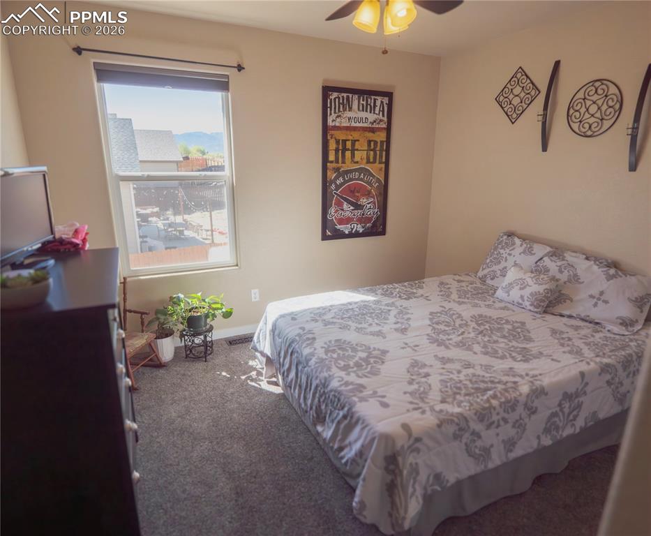 Image 21 of 32: Bedroom with dark colored carpet and a ceiling fan