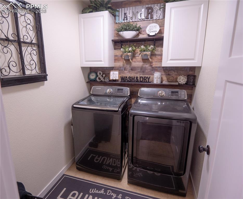 Image 22 of 32: Laundry room featuring washing machine and clothes dryer, cabinet space, an