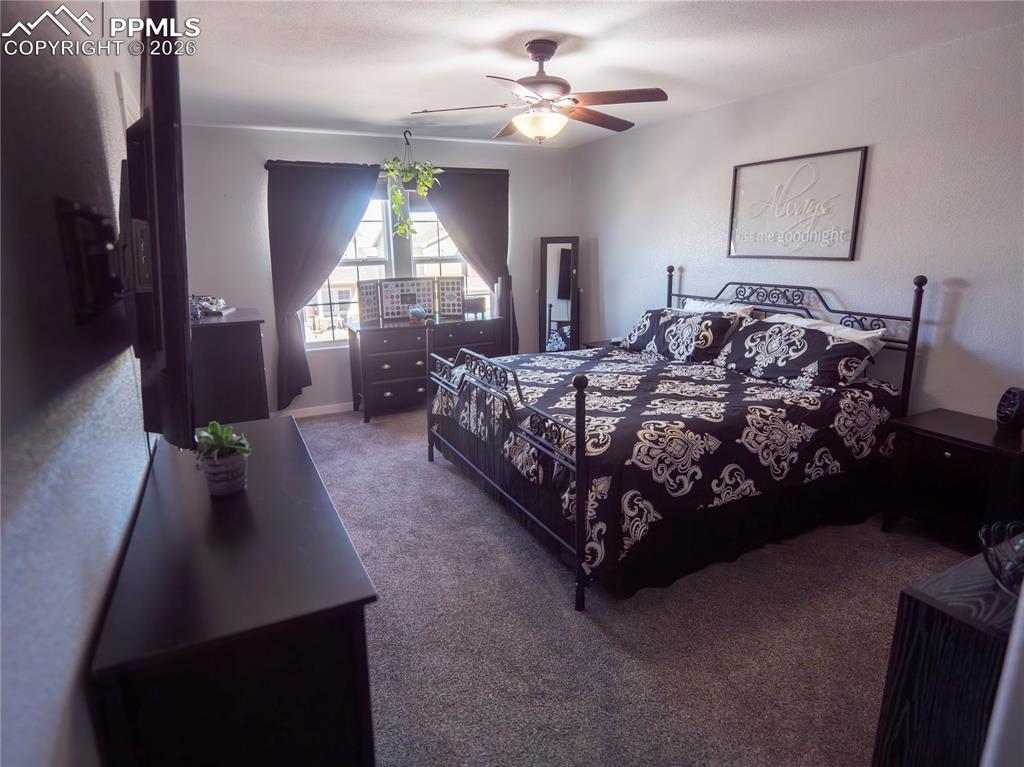 Image 23 of 32: Carpeted bedroom with ceiling fan