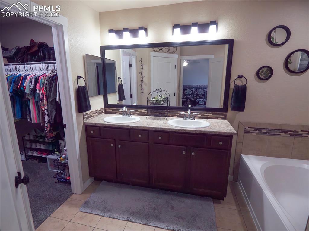 Image 26 of 32: Full bathroom featuring double vanity, a spacious closet, a bath, light til