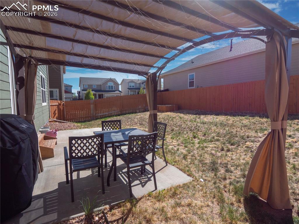 Image 27 of 32: Fenced backyard featuring a patio area, a grill, outdoor dining area, and a