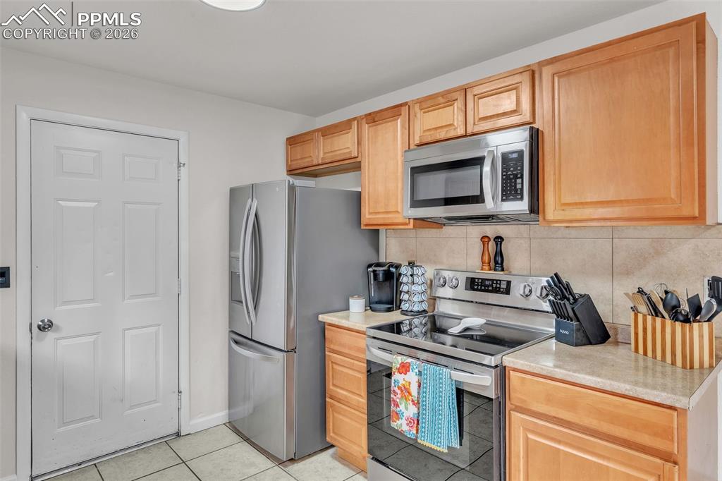 Image 18 of 44: Kitchen with stainless steel appliances, light countertops, light tile patt