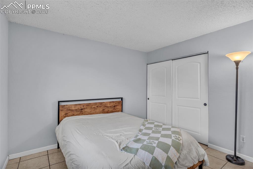 Image 27 of 44: Bedroom featuring a textured ceiling, light tile patterned floors, and a cl