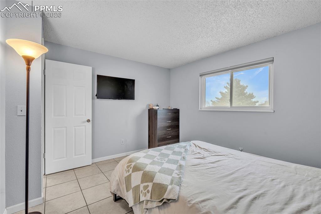 Image 28 of 44: Bedroom with a textured ceiling and light tile patterned floors