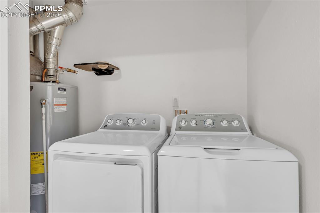 Image 33 of 44: Laundry room featuring water heater and washing machine and dryer