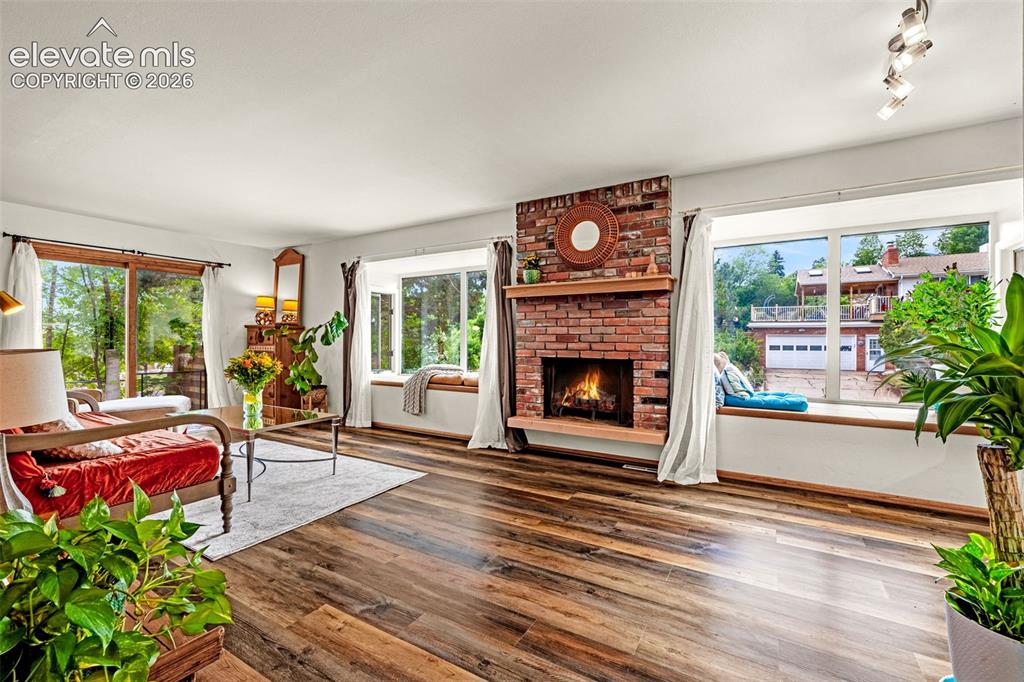 Image 12 of 38: Living area featuring wood-finish flooring, a brick fireplace with a wood m